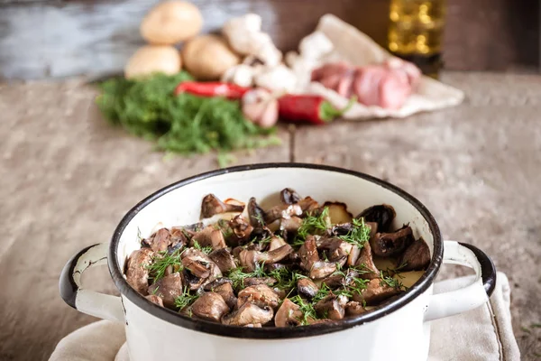 Dish of potatoes with mushrooms on a wooden background and raw i — Stock Photo, Image