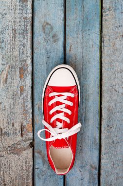 Mavi ahşap arka plan üzerinde kırmızı retro spor ayakkabı