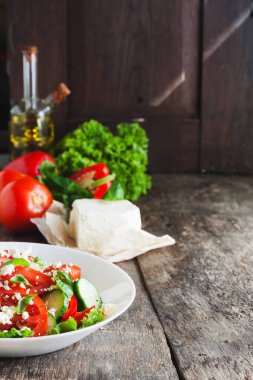 Ahşap arka plan, bir sayı üzerinde beyaz bir tabak içinde Shopska salata 