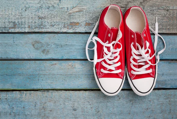 Mavi ahşap arka plan üzerinde gevşek örgüler ile kırmızı retro spor ayakkabı