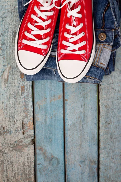 Rote Retro-Turnschuhe und Jeans auf blauem Holzhintergrund — Stockfoto