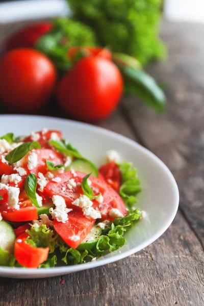 Ahşap arka plan, bir sayı üzerinde beyaz bir tabak içinde Shopska salata 