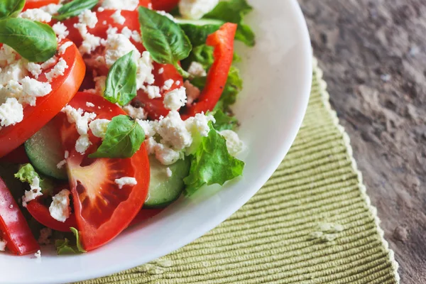 Ahşap arka plan, beyaz bir tabağa Shopska salata yakın çekim