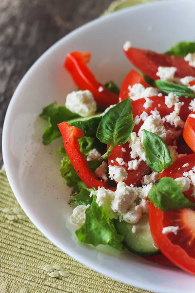 Ahşap arka plan, beyaz bir tabağa Shopska salata yakın çekim