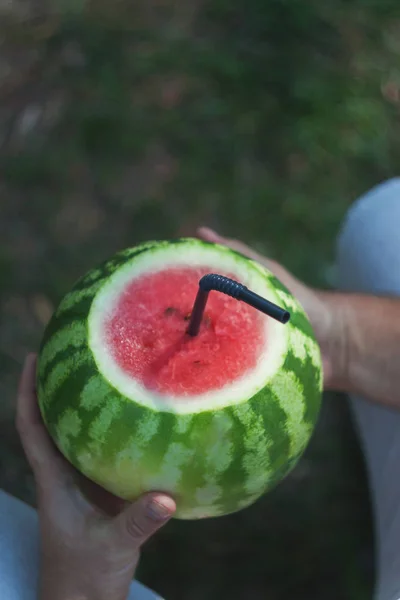 En ung man innehar en hel vattenmelon med halm för att dricka, — Stockfoto