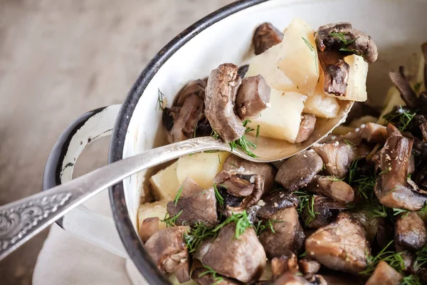 Dish of potatoes with mushrooms on a wooden background, close-up — Stock Photo, Image