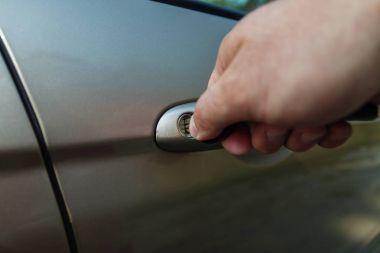 Bir adamın eli arabanın kapısını anahtarla açar.