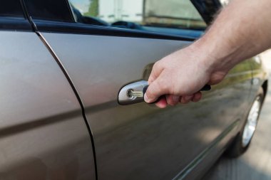 Bir adamın eli arabanın kapısını anahtarla açar.
