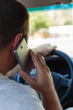 bir araba sürüş sırasında cep telefonuyla konuşan adam