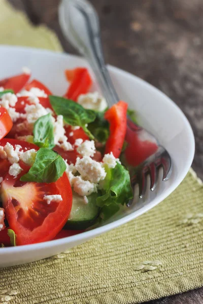 Ahşap arka plan, beyaz bir tabağa Shopska salata yakın çekim