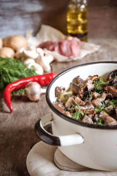 Dish of potatoes with mushrooms on a wooden background and raw i — Stock Photo, Image