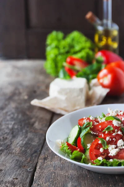 Ahşap arka plan, bir sayı üzerinde beyaz bir tabak içinde Shopska salata 