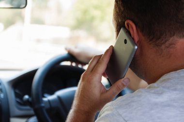 bir araba sürüş sırasında cep telefonuyla konuşan adam