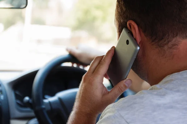 bir araba sürüş sırasında cep telefonuyla konuşan adam