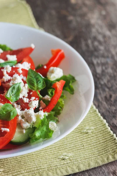 Ahşap arka plan, beyaz bir tabağa Shopska salata yakın çekim