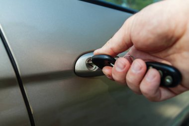 Bir adamın eli arabanın kapısını anahtarla açar.