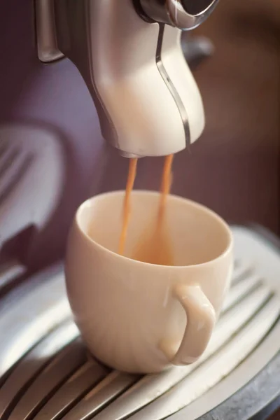 Белая чашка, стоящая на решетке кофемашины с кофе — стоковое фото