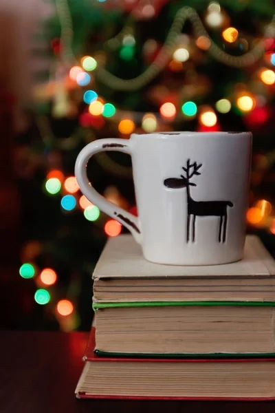 Christmas celebration with cup and gift box on books over bokeh — Stock Photo, Image