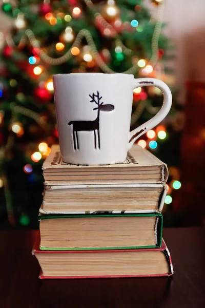Christmas celebration with cup and gift box on books over bokeh — Stock Photo, Image