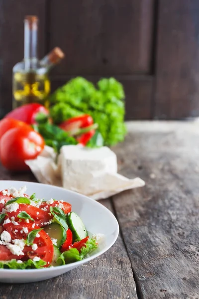 Ahşap arka plan, bir sayı üzerinde beyaz bir tabak içinde Shopska salata 