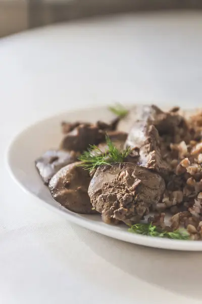 Stewed chicken liver and buckwheat porridge on a white tableclot — Stock Photo, Image