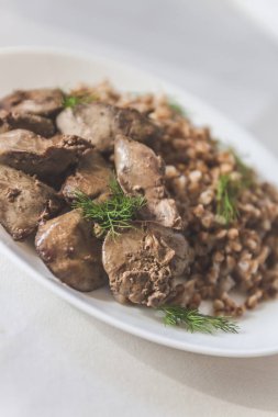 Beyaz bir tableclot üzerinde tavuk karaciğer ve buğday lapası Komposto