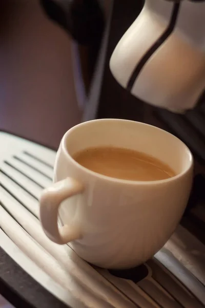 Λευκό φλιτζάνι στέκεται πάνω από το τρίψιμο του καφετιέρα με καφέ — Φωτογραφία Αρχείου