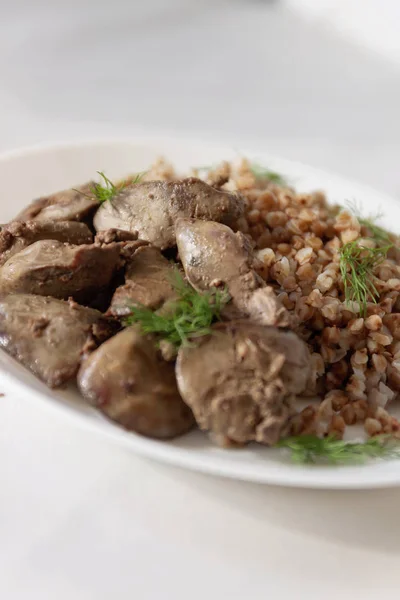 Stewed chicken liver and buckwheat porridge on a white tableclot — Stock Photo, Image