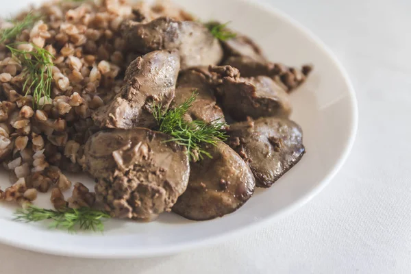Stewed chicken liver and buckwheat porridge on a white tableclot — Stock Photo, Image