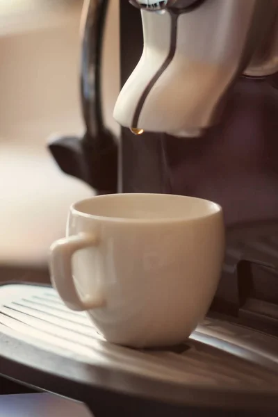 Copo branco de pé na grade da máquina de café com café — Fotografia de Stock