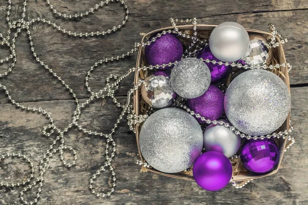 Paarse kerstballen en zilver, kralen liggen in een houten mand — Stockfoto