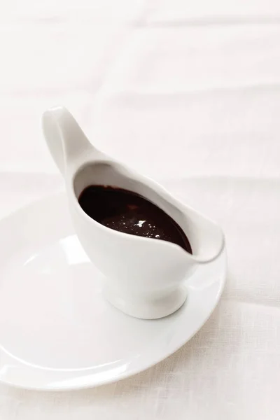 Шоколадный соус в белом фарфоровом соусе на белом бэкгре — стоковое фото