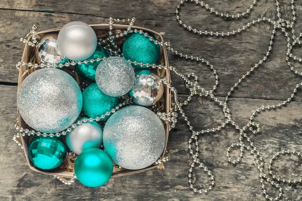 green Christmas balls and silver, beads lie in a wooden basket t