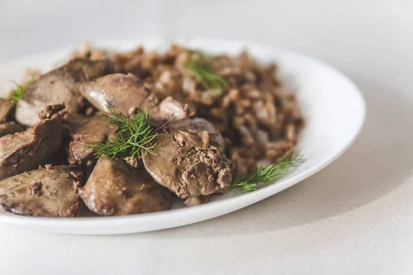 Stewed chicken liver and buckwheat porridge on a white tableclot — Stock Photo, Image