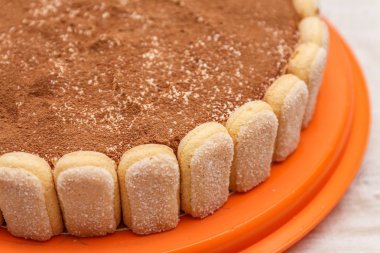 Yuvarlak tiramisu pasta kakao powd serpin Beyaz ahşap masa üzerinde