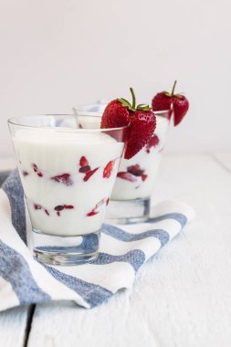 Tatlı yoğurt ve çilek katmanları bir cam üzerinde mavi bir şerit