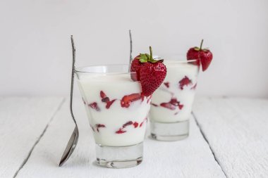 Tatlı yoğurt ve çilek katmanları bir cam üzerinde mavi bir şerit
