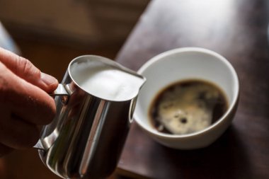 Sütlü kahve bir fincan içine dökülen adam