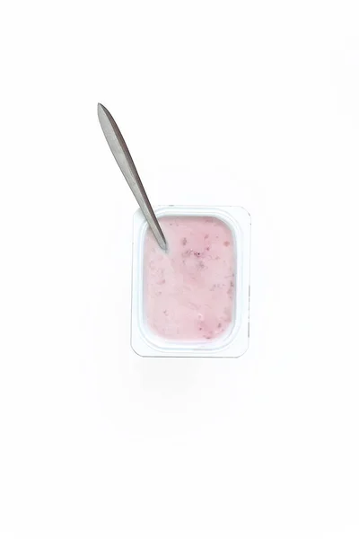Container with strawberry yogurt and spoon, top view, isolated o — Stock Photo, Image
