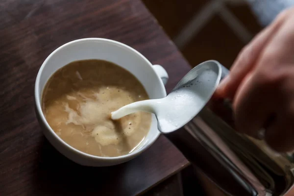 Uomo versando in una tazza di caffè con latte — Foto Stock