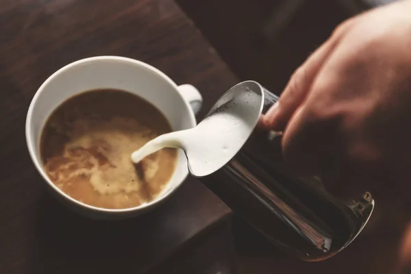 Hombre vertiendo en una taza de café con leche — Foto de Stock