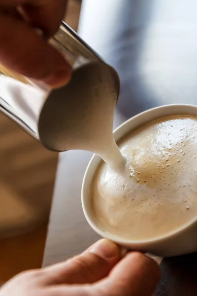 Uomo versando in una tazza di caffè con latte — Foto Stock