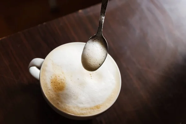 Kopp kaffe med skum som rörs av en mänsklig hand — Stockfoto