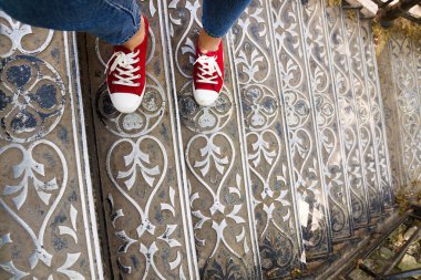 kot pantolon ve bir antika metal merdiven üzerinde kırmızı spor ayakkabılar bacaklar. Hedef