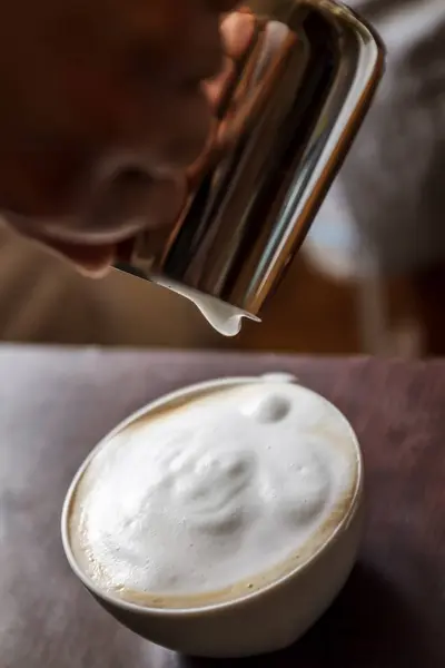 Homem derramando em uma xícara de café com leite — Fotografia de Stock