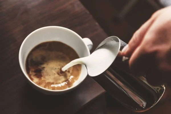 Mann gießt in eine Tasse Kaffee mit Milch — Stockfoto