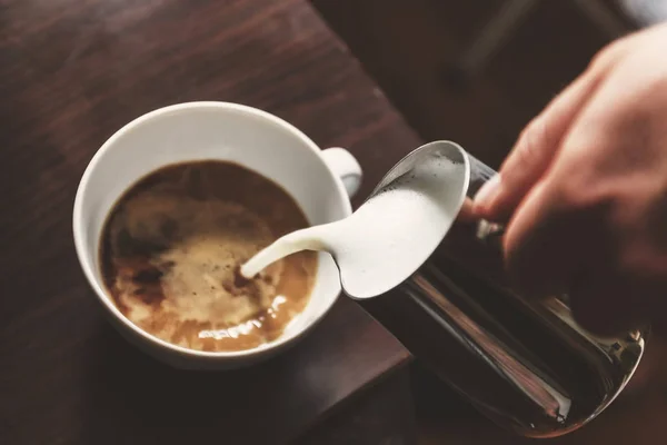 Homem derramando em uma xícara de café com leite — Fotografia de Stock