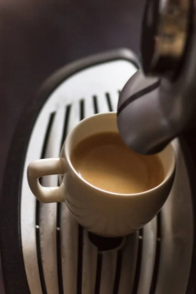 Coupe blanche debout sur la grille de la machine à café avec café — Photo