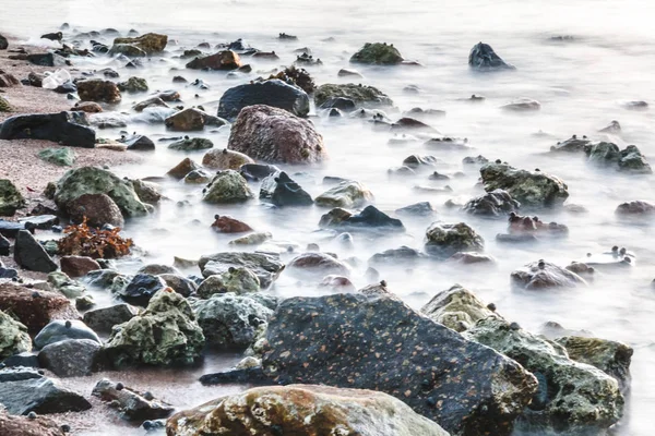 stock image long exposure of sea and rocks and stones, teal tone