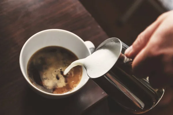 Mann gießt in eine Tasse Kaffee mit Milch — Stockfoto